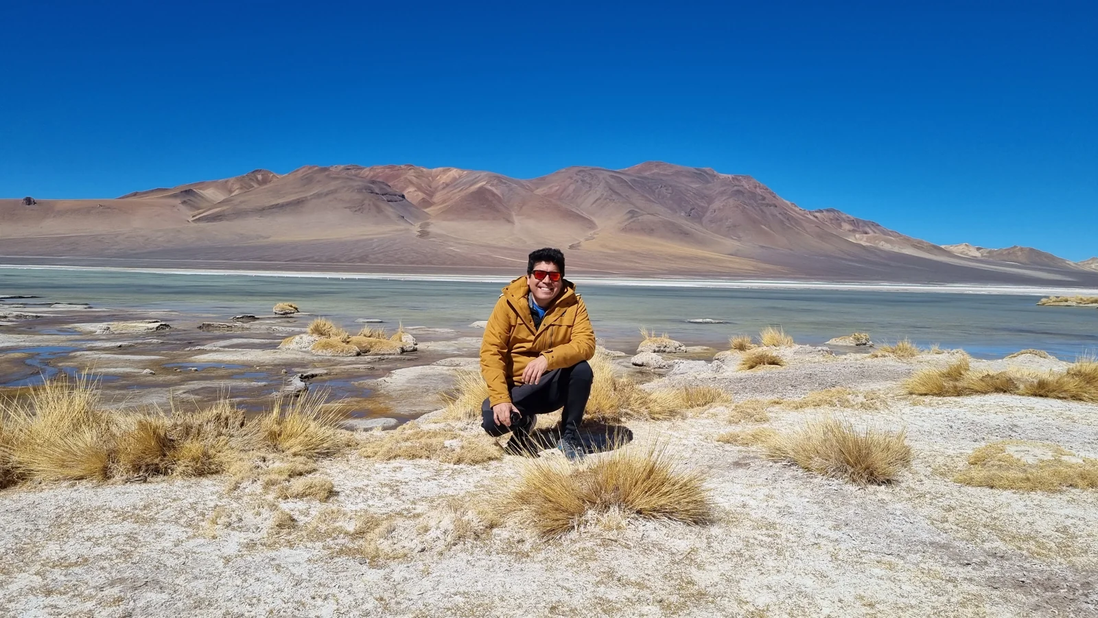 Hernán Cáceres junto a una laguna de altura y montañas